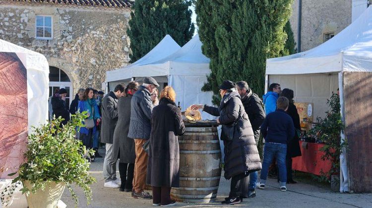 Des barnums blancs abritant les stands de producteurs dans la cour de Domaine Arton en 2023, avec des personnes en train de visiter et déguster